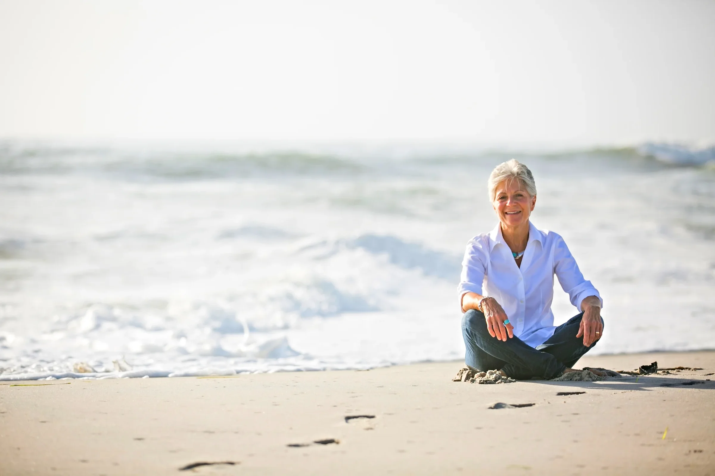 Nancy Devine sitting on the beach, smiling