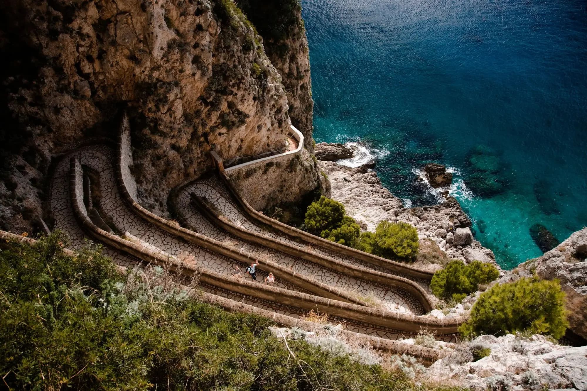 A winding cliffside path above a turquoise sea