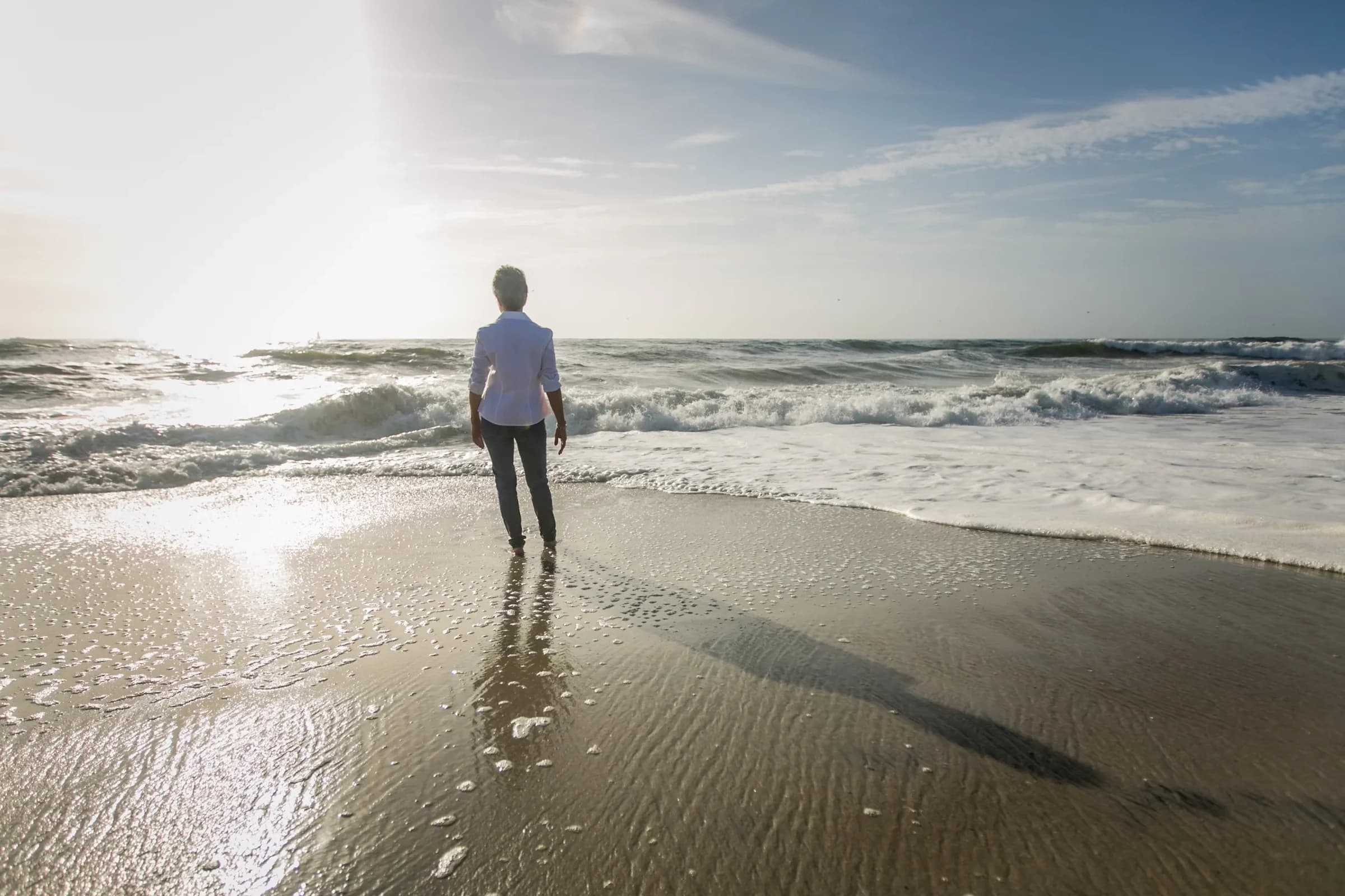 Nancy Devine standing at the water's edge, looking out at the waves