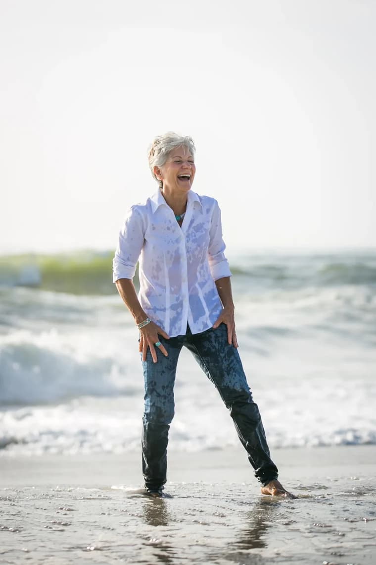 Nancy Devine laughing as she stands in the surf